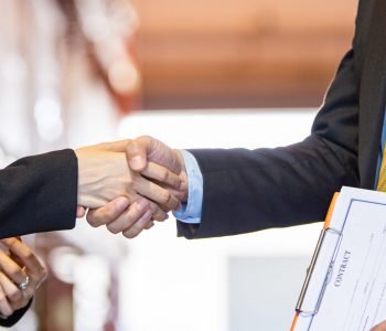 Business people handshake to greeting, closing deal or contract agreement at product warehouse. import, export logistic concept.